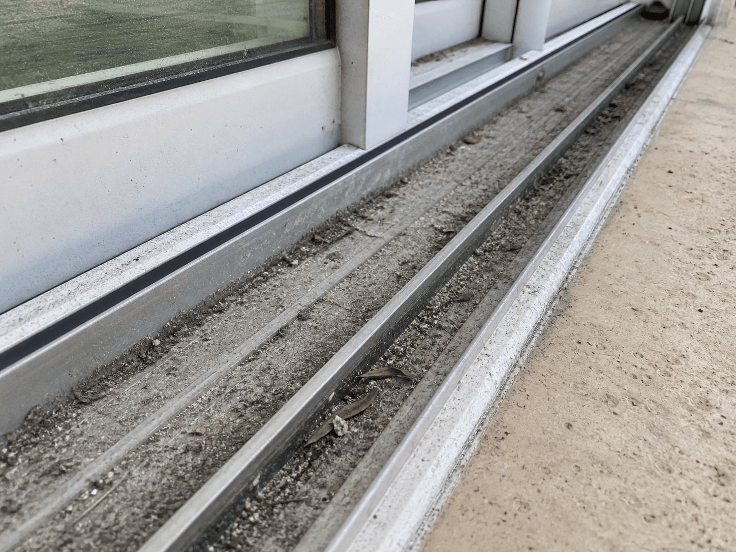 Illustration before track cleaning showing sand, dust, and debris in a sliding door track at a South Florida property